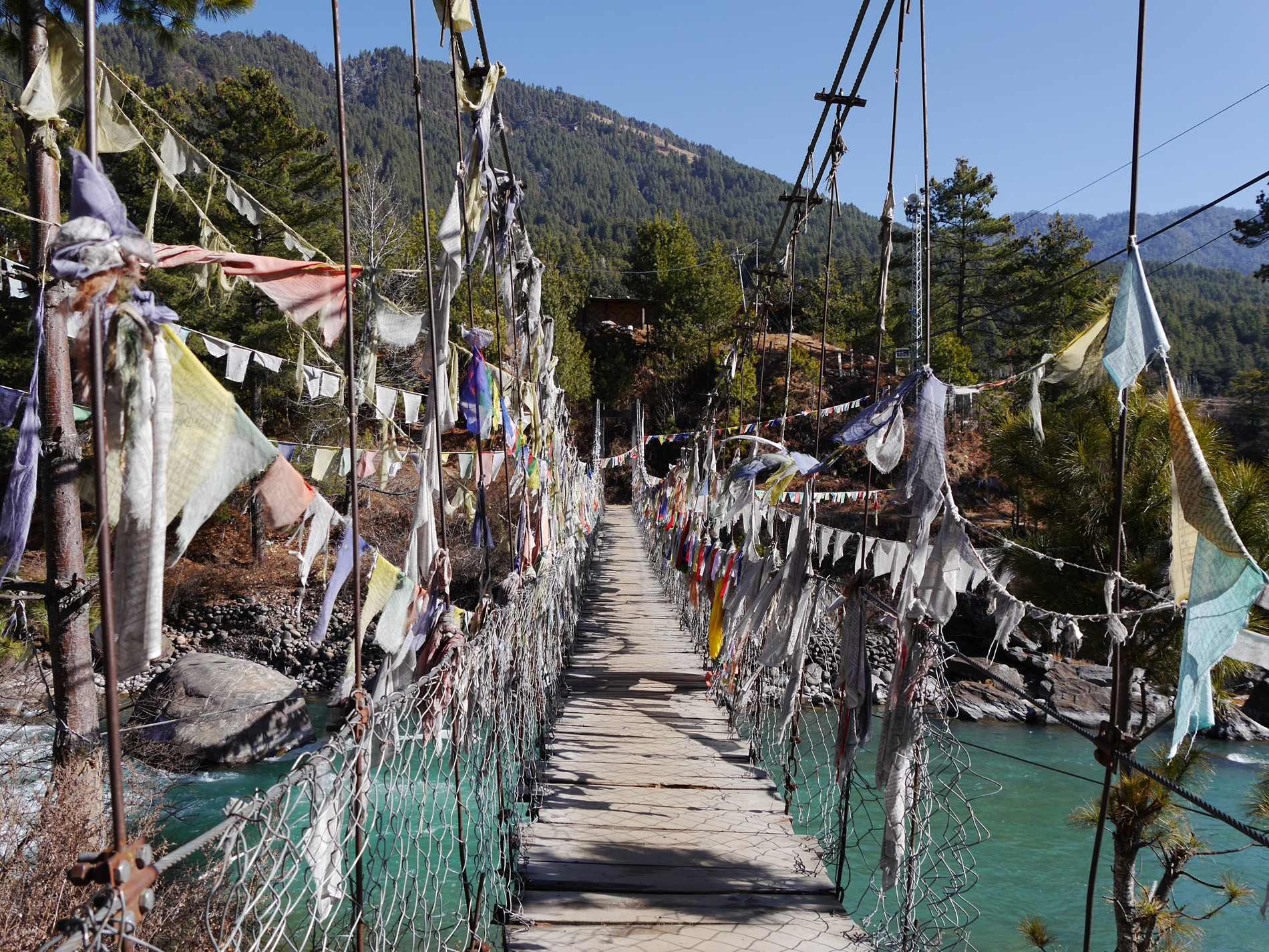 Brücke mit Gebetsfahnen in Bumthang mit Bergen im Hintergrund
