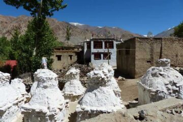 weiße Steinskulpturen vor Bergdorf in Ladakh