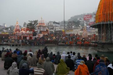 Menschen sitzen am Ganges beim Parmarth Niketan Ashram