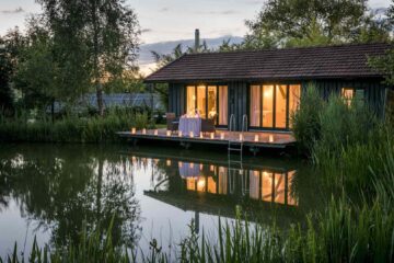 Innen beleuchtetes Haus mit Terrasse am See bei Kerzenschein