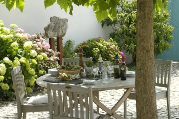 Gedeckter Tisch von Blumen umrankt unter Baum