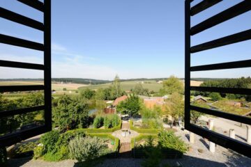 Blick durch das geöffnete Fenster auf den grünen Innenhof