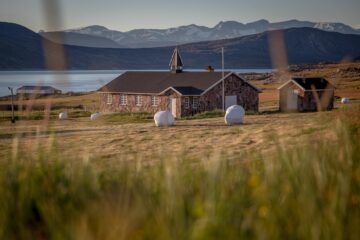 Kirche aus Tein vor Bergkulisse und Fjord