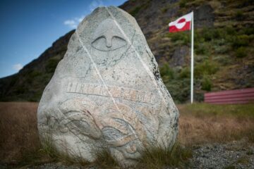 Stein mit Gesicht behauen und rot-weiße Fahne