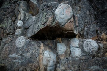 Weiße Gesichter in graue, massive Steinmauer gehauen
