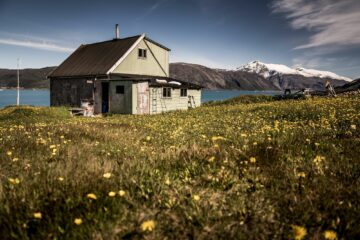 Graues Holzhaus mit Fjord-Blick inmitten Wiese