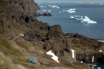 Wandergruppe an Felsmassiv vor der Küste