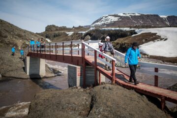 Wanderer queren auf Holzbrücke den Fjord