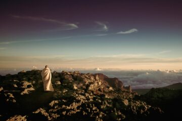 Frau in weißem Gewand auf Felsen