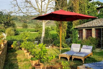 roter Sonnenschirm mit zwei Liegen inmitten von grünem Garten