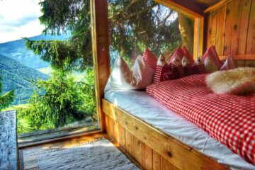 Koje im Baumhaus mit rot-weiß-karierter Bettwäsche und Panoramafebster