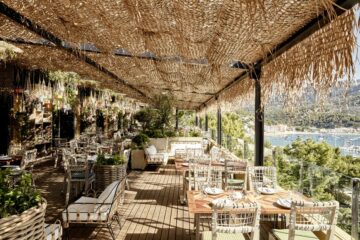 Palmgedeckte Terrasse bestuhlt mit Blick auf die Bucht