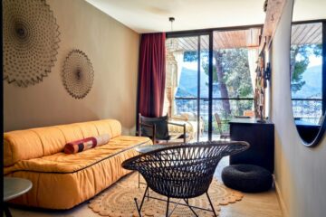 Wohnraum mit gelbem Sofa und schwarzem Rattanstuhl
