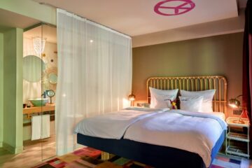 Bett mit abgetrenntem Waschraum und pinkem Peace-Zeichen an Decke