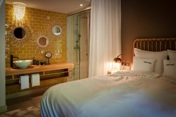 Bett mit beleuchteter Waschecke und gelb gefliester Wand mit Spiegeln
