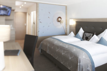 Zimmer mit Bett und Pusteblumewand