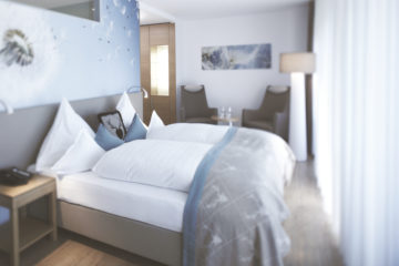 Zimmer mit Doppelbett und Pusteblumentapete