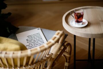 Teetasse mit Teebeutel auf Tisch und Stuhl mit Zeitschrift