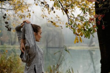 Frau dehnt sich am Wasser im Wald