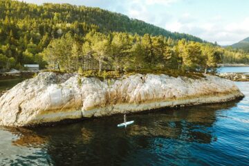 SUP-Paddler fährt an großem Stein entlang