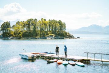 Mann und Frau mit Anorak am Steg mit SUPs im Wasser