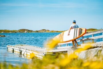 Mann mit Sup-Board unter dem Arm