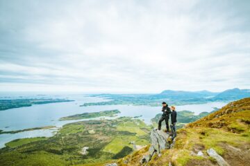 Frau und Mann stehen am Berg hoch über dem Fjord