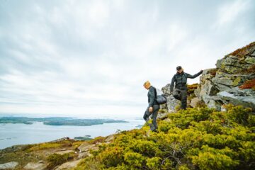 Mann und Frau wandern mit Blick auf Fjord