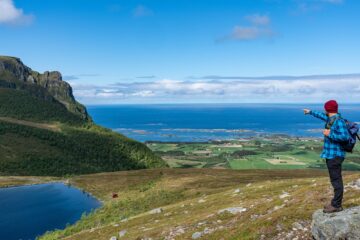 Mann in Wanderkleidung zeigt zum blauen Meer