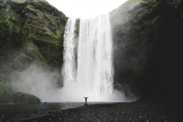 Frau steht unter Wasserfall