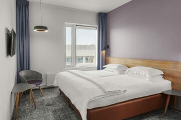 Doppelbett und fliederfarbene Wand
