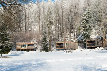 Drei Holzhäuser im Wald