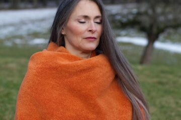Frau in orangener Wolldecke meditiert