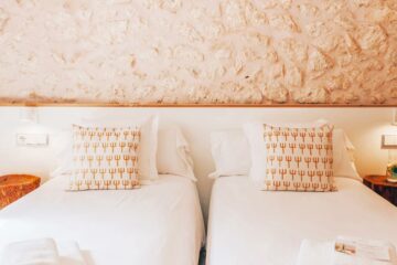 Betten vor cremefarbener Steinwand mit Kissen