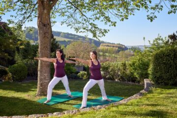 Zwei Frauen in Yoga-Pose im Garten