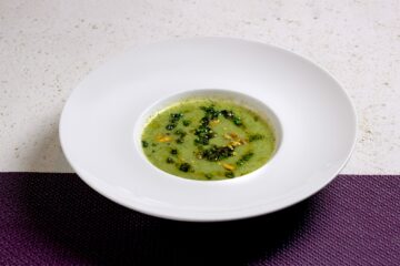Teller mit grüner Suppe und Kräutern