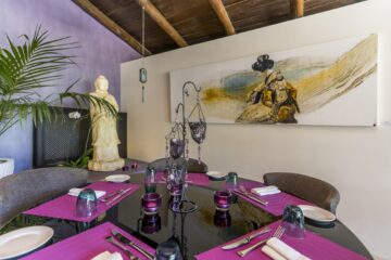 Brauner Tisch mit pinken Platzsets und chinesisches Gemälde an der Wand