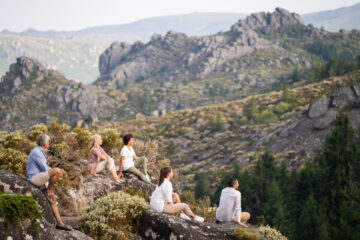 Gruppe sitzt auf Berg und schaut in die Weite