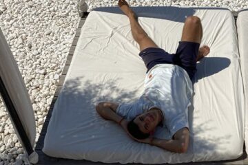Mann liegt auf Sonnenbett auf weißem Kies