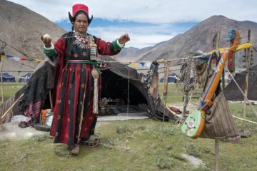 Frau mit Wollknäuel in traditioneller Tracht vor dem Zelt
