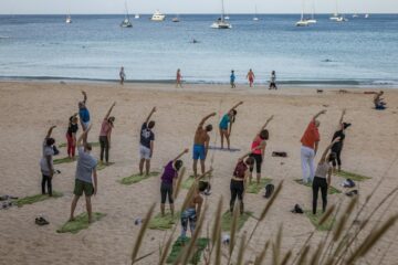 Gruppe übt Yoga am Strand