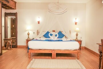 Bett mit Moskitonetz und blauen Kissen