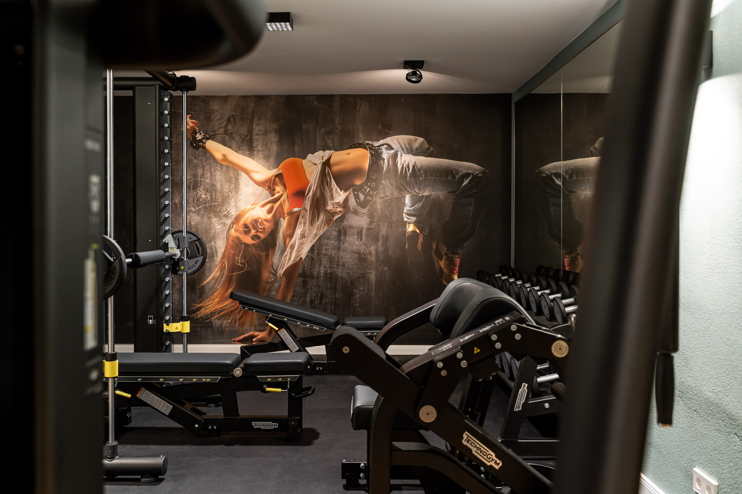 Fitnessraum mit Geräten und Poster mit Frau