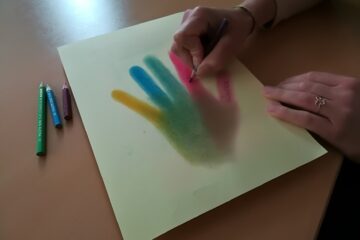Frau beschreibt Fingerflächen auf farbigem Händeabdruck