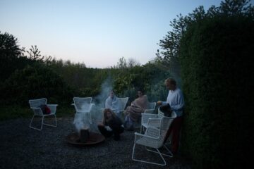 Frauen im Kreis auf Stühlen und rauchendes Feuer in der Mitte