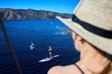Frau schaut auf SUP-Paddler im blauen Meer