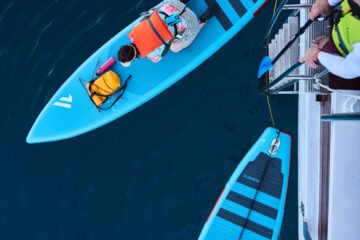 Mann auf Boot steht an Leiter um zum SUP darunter zu steigen