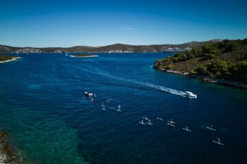 Blick auf Insel, SUP-Gruppe und Meer und Beiboot