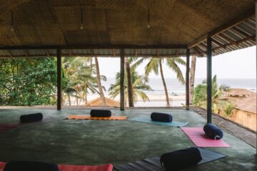 Offener Bereich mit Yogamatten und Kissen und Blick zum Strand und zum Meer