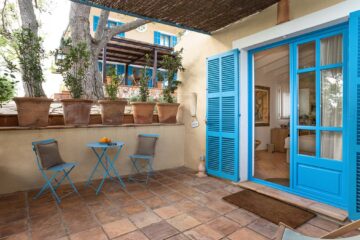Terrasse mit blauen Stühlen und Tisch und blaue Fensterläden